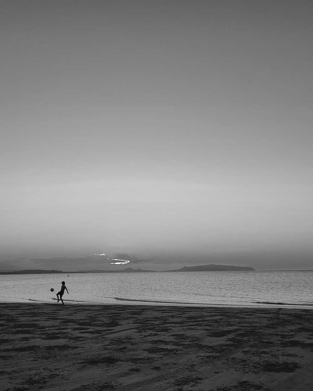 foot-beach-queensland A child playing football on the beach, Mackay, Queensland, Australia